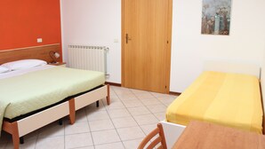 Ein Zimmer mit zwei Betten, einem Holztisch, einem Heizkörper und einer Tür.