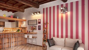 Una cocina con barra, un sofá blanco y pared a rayas.