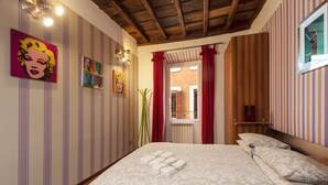 Una habitación de hotel con cama, paredes a rayas y obras de arte.