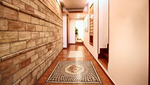 Un pasillo con pared de ladrillo, alfombra estampada y una escalera.