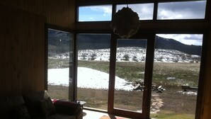 A room with a large window offering a view of a snowy landscape and mountains. - Your Home In The Andes (San Martin de los Andes)