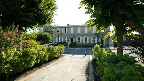 Un bâtiment portant l’inscription « MAISON DU SAUTERNES », avec une allée pavée et une végétation luxuriante.