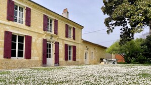 Un immeuble de deux étages avec des volets rouges et une façade en pierre.