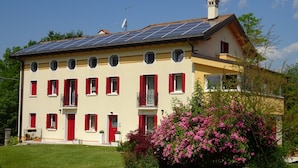 Un bâtiment à deux étages, doté d’un toit plat, de panneaux solaires et d’une porte rouge.