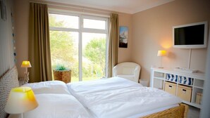 Una camera d'albergo con un letto grande, una televisione, una sedia e una finestra con tende.
