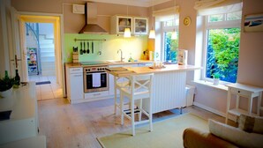 Una cucina compatta con mobili bianchi, un'isola centrale con sgabelli da bar, un forno integrato e una finestra vista verde.