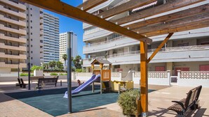 An outdoor patio area with a children's play structure, benches, and a brick floor. - FRONTLINE APARTMENT WITH BIG TERRACE AND BEATIFULL SEA VIEWS (Calpe)