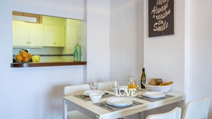 A dining area with a white table set for two, a kitchen in the background, and a motivational quote on the wall. - FRONTLINE APARTMENT WITH BIG TERRACE AND BEATIFULL SEA VIEWS (Calpe)