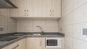 Una cucina moderna con pensili in legno chiaro, un lavello in acciaio inossidabile e un forno a microonde integrato.