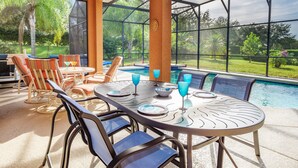 Eine Terrasss mit Poolbillard, Stühlen und einem überdachten Bereich mit Blick auf Pool und Garten.