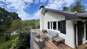 A modern house with a deck, outdoor furniture, and a view of the surrounding landscape.