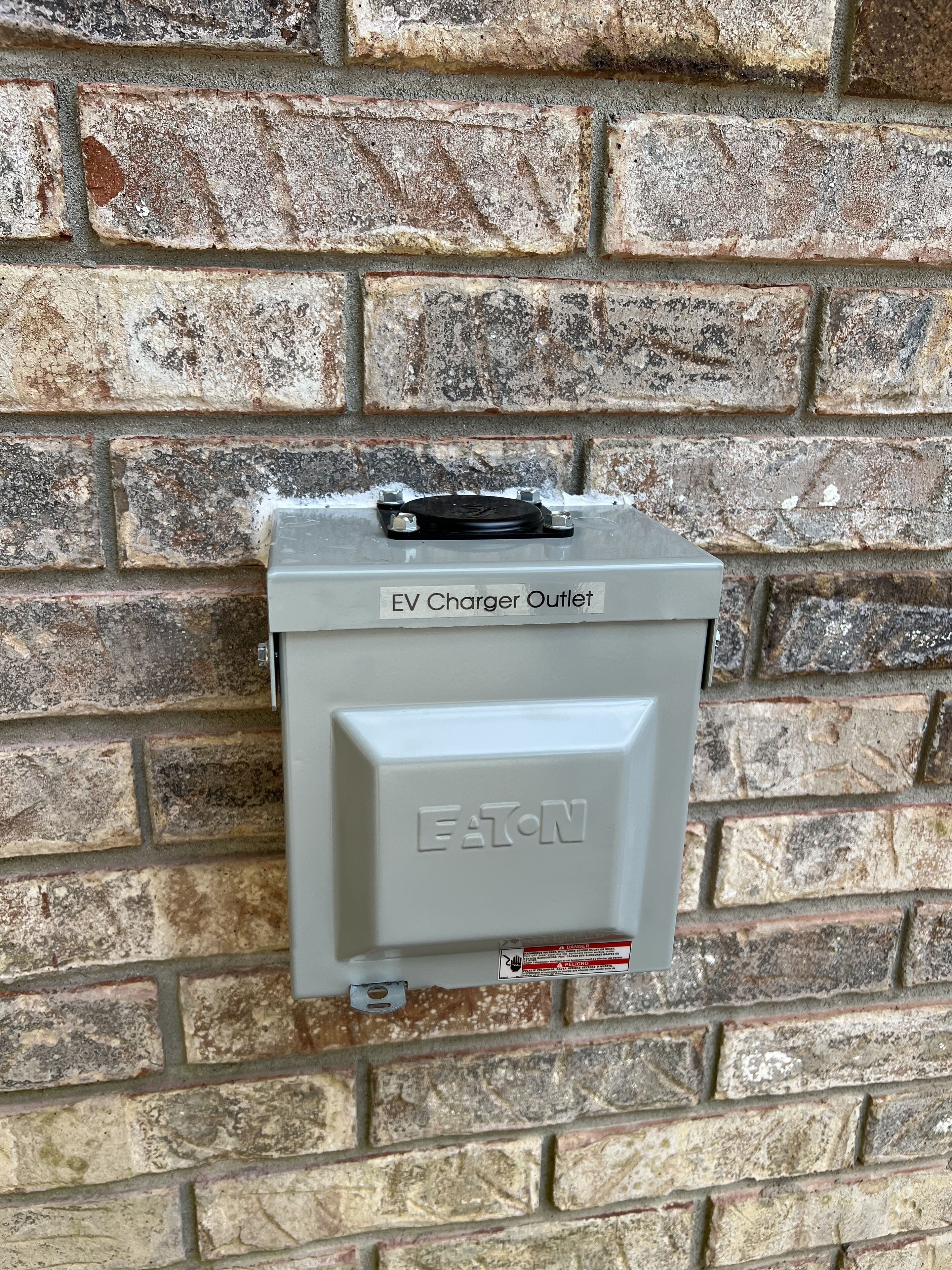 Une borne de recharge pour véhicules électriques fixée à un mur en briques.