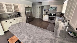 A modern kitchen with white cabinetry, a stainless steel refrigerator, an oven, and a sink.
