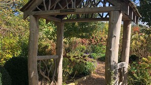 A wooden gazebo with a sign reading "Hayes' Garden" in a garden setting.