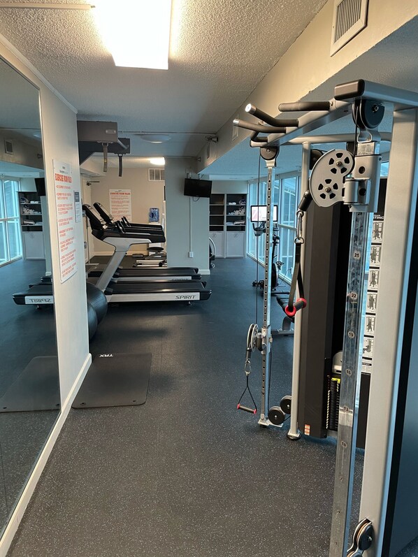 A gym with treadmills, a weight machine, and a wall-mounted TV.