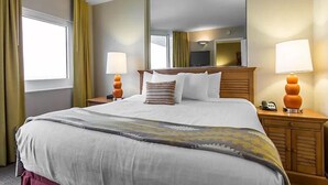 Ein Hotelzimmer mit einem großen Bett, zwei Nachttischen mit Lampen, einem Flachbildfernseher und einem großen Spiegel über dem Bett.