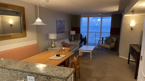 Ein Hotelzimmer mit Essbereich, einer Couch, einem Sessel, einem Tisch und Blick auf das Meer.