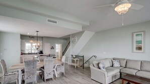 A spacious living room with a dining area, a staircase, and a kitchen in the background. - 🌞Oceanfront rooftop getaway 🏖️Steps to sand 🐶Dog Friendly⚡️EV charger (North Topsail Beach)