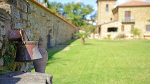 A stone wall with a rustic metal bucket and a large clay pot.