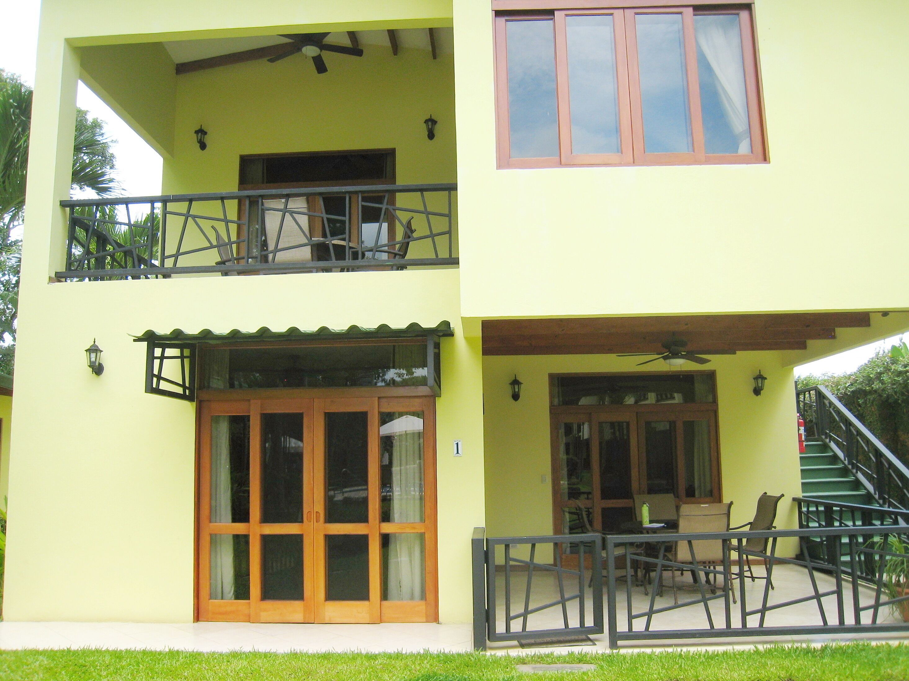 Ein zweistöckiges Gebäude mit Balkon, überdachter Terrasse und Treppe.