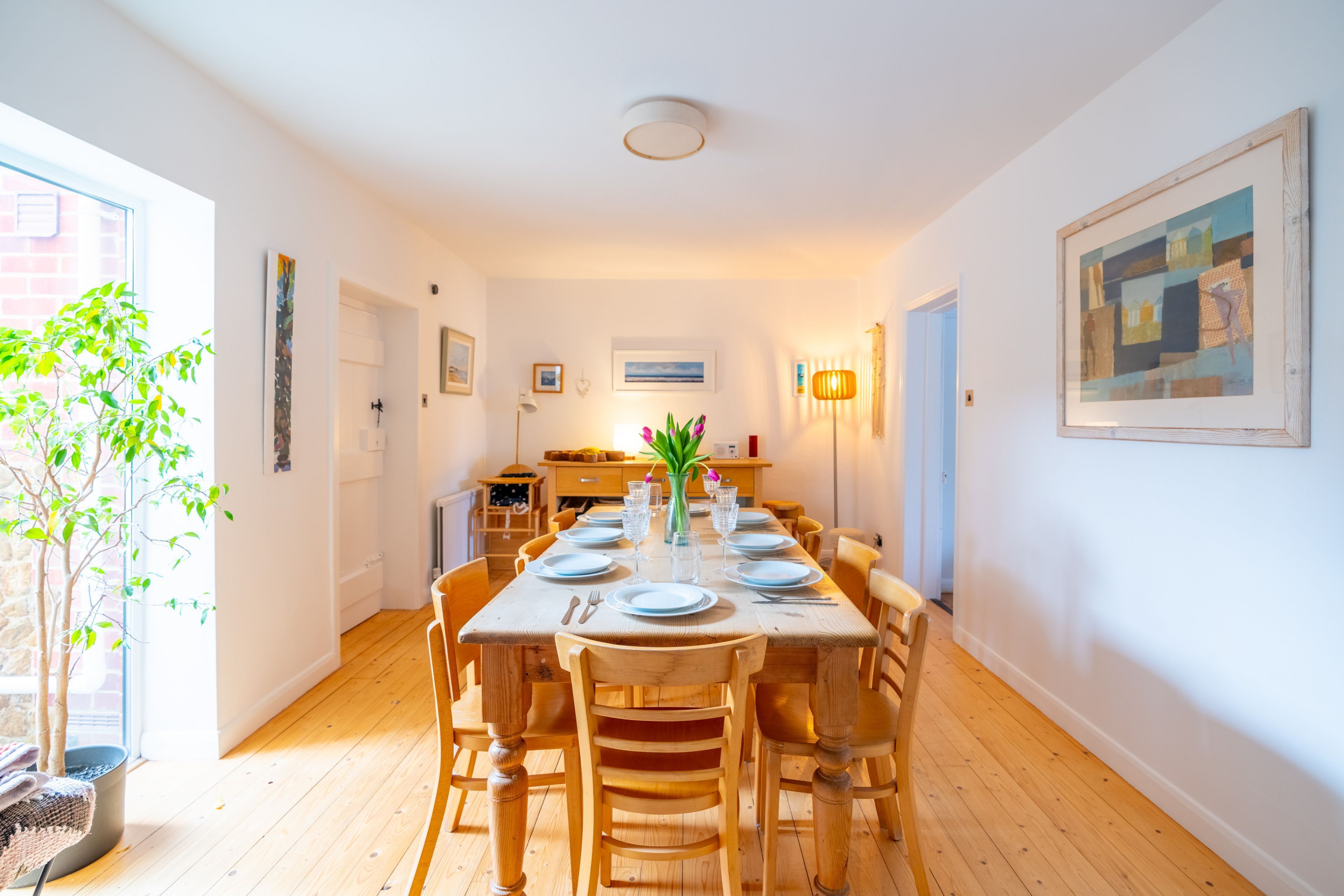 Un coin repas avec une table en bois dressée pour six personnes, entourée de chaises en bois.