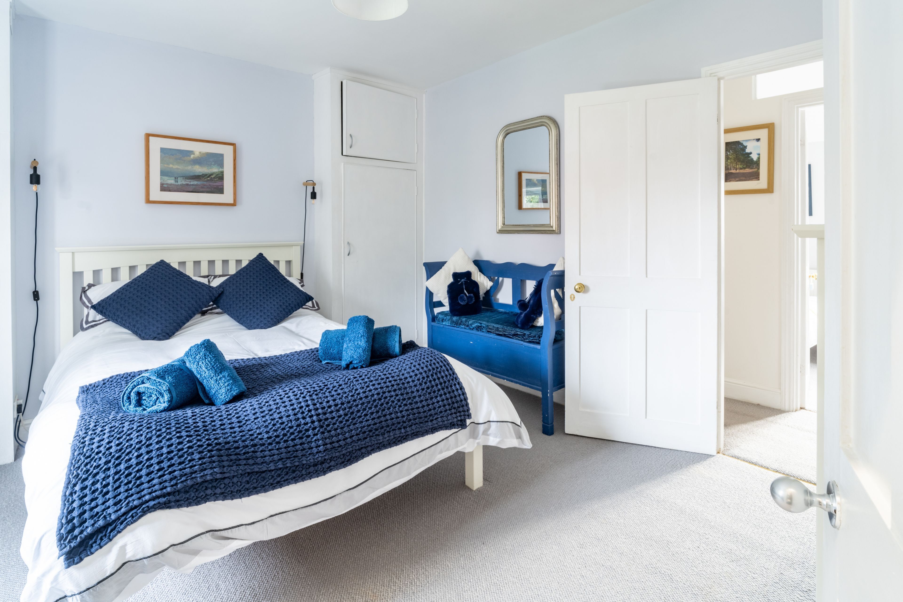 Une chambre à coucher avec un lit, une commode, un miroir et une porte.