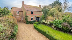 A two-story house with a gravel driveway and a well-maintained garden. - Sybil Cottage, Holme-next-the-Sea, Norfolk (Hunstanton)