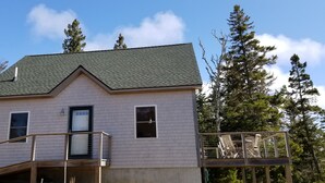 A two-story house with a balcony and a staircase leading to the upper floor. - Tranquil oceanfront cottage on Wohoa Bay (Addison)