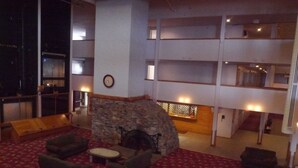 Eine geräumige Lobby mit Kamin aus Stein, bequemen Sitzgelegenheiten und einer hohen Decke mit mehreren Ebenen.
