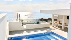 Una piscina sul tetto con vista sul mare, un'area ristoro con posti a sedere all'aperto e un piccolo giardino con piante in vaso.