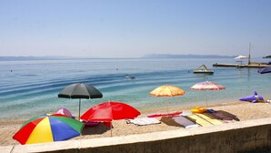 Una spiaggia con acque cristalline, diversi ombrelloni colorati e lettini.
