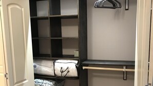 A walk-in closet with open shelves, a hanging rod, and a storage bin. - Rider’s Rest # 2 within 2 miles of Tryon International Equestrian Center (Rutherfordton)