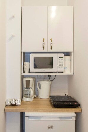 Eine Küchenzeile mit einer Mikrowelle, einer Kaffeemaschine und einem kleinen Kühlschrank.