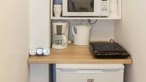 Une petite cuisine équipée d’un four à micro-ondes, d’une machine à café, d’une bouilloire et d’un petit réfrigérateur.