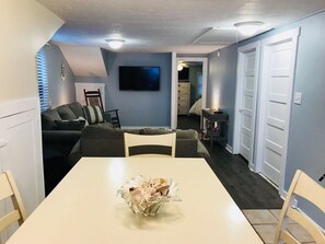 Cozy living space with a dining area, featuring a dining table, comfortable sofa, and flat-screen TV.