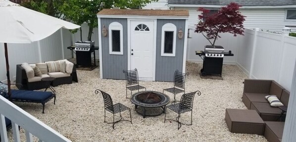 Relax by the fire pit in a cozy outdoor space with a storage shed and covered patio.