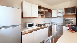 A modern kitchen with white cabinets, a microwave, a gas stove, and a built-in oven.