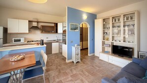 A compact living space with a kitchenette, dining area, and a seating area with a TV.
