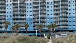 A beachfront hotel with multiple balconies and a sandy walkway leading to the entrance. - Partial View 1 BR 1 BA, 8/28/26 to 9/4/26, Week 35, Fri-Fri, Room # 1302, (North Myrtle Beach)