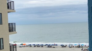 A view of a beach with umbrellas and people from a building with balconies. - Partial View 1 BR 1 BA, 8/28/26 to 9/4/26, Week 35, Fri-Fri, Room # 1302, (North Myrtle Beach)