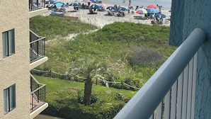 A view of a beach from a balcony with a building in the foreground. - Partial View 1 BR 1 BA, 8/28/26 to 9/4/26, Week 35, Fri-Fri, Room # 1302, (North Myrtle Beach)
