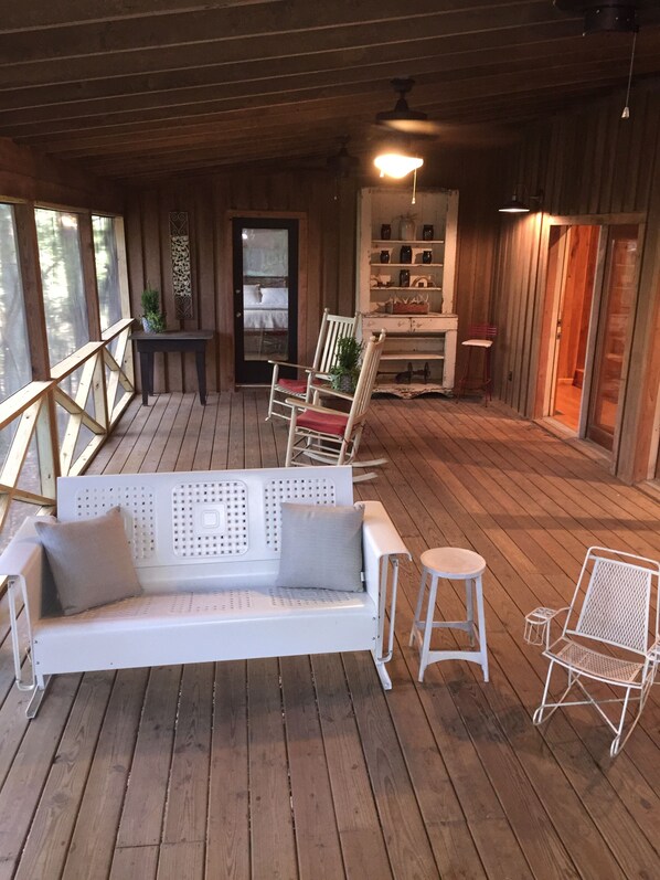 A wooden deck with a white sofa, two white chairs, and a small table. - Oxford Retreat - 4B/4B Newly Renovated Cabin 15 Minutes From Downtown Oxford! (Batesville)