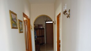 A hallway with a marble floor, wooden doors, and a chandelier. - DIAMOND - ITALY - SUN AND SEA (Diamante)