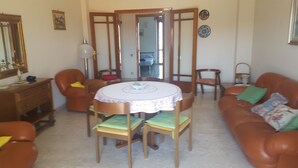 A living room with a round table, two brown leather sofas, and a wooden cabinet. - DIAMOND - ITALY - SUN AND SEA (Diamante)