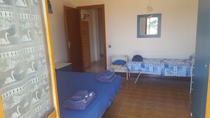 A room with two beds, a small table, and a mirror on the wall. - DIAMOND - ITALY - SUN AND SEA (Diamante)