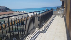 A balcony with a metal railing overlooking a beach and buildings. - DIAMOND - ITALY - SUN AND SEA (Diamante)