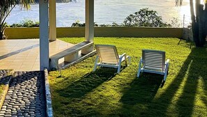Un área de estar al aire libre techada, con dos sillas y un patio con baldosas.