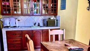 Una cocina con armarios de madera, microondas, fregadero y una mesa de comedor con sillas.
