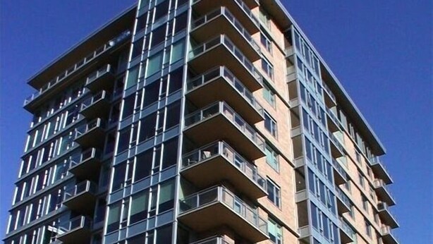 Een meerlaags gebouw met balkons, grote ramen en een modern architectonisch ontwerp.