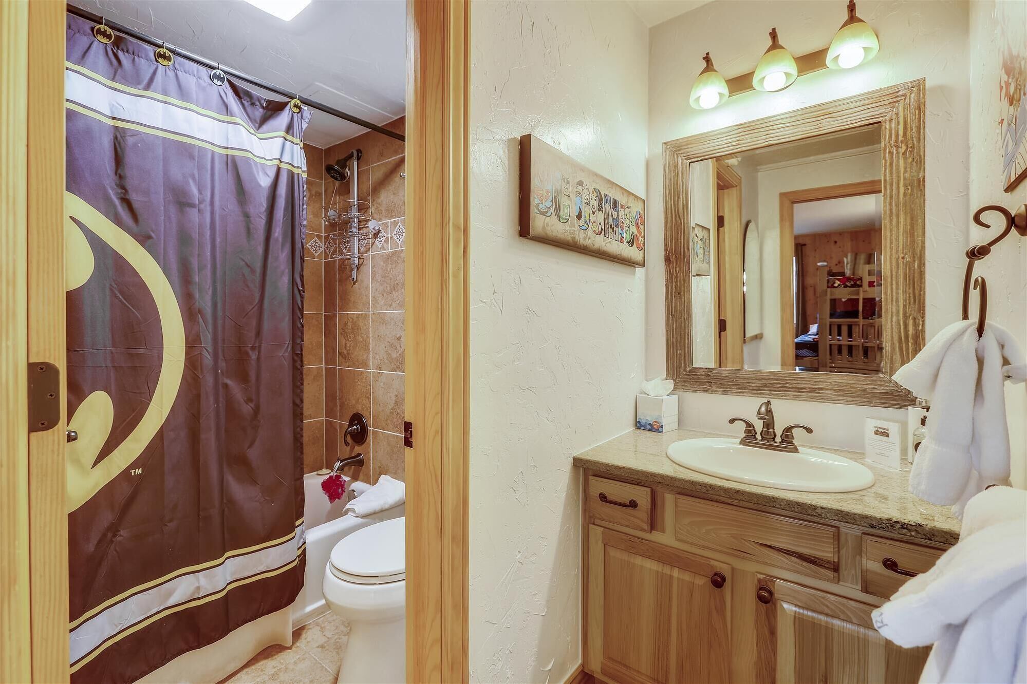 Une salle de bain équipée d’un rideau de douche, de toilettes, d’un lavabo et d’un miroir.